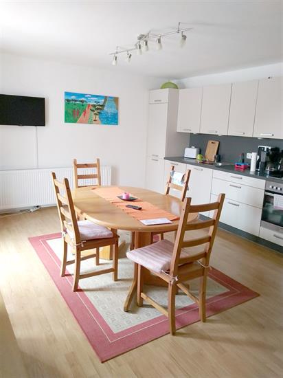 Bild zeigt einen Raum mit Einbauküche und Esstisch mit Stühlen